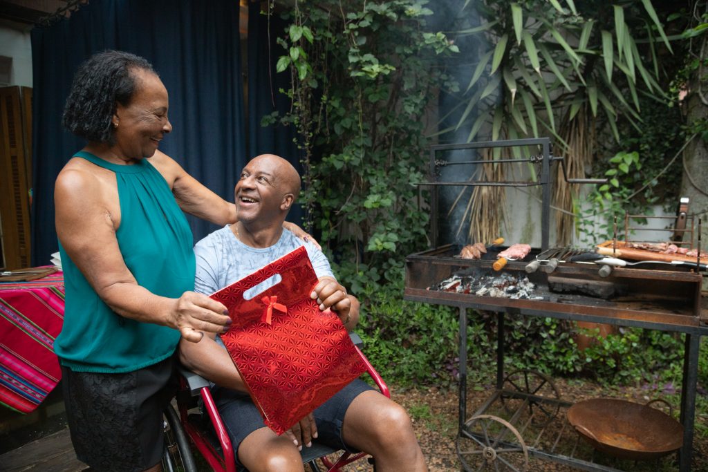 Mother giving birthday present to her Son at barbecue party