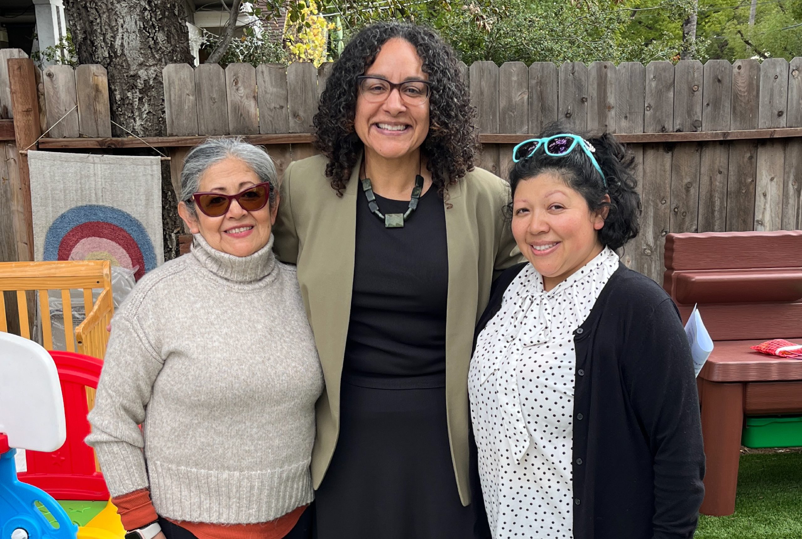 Secretary Kim Johnson, Esperanza and Scarlett standing in the yard of their family child care home