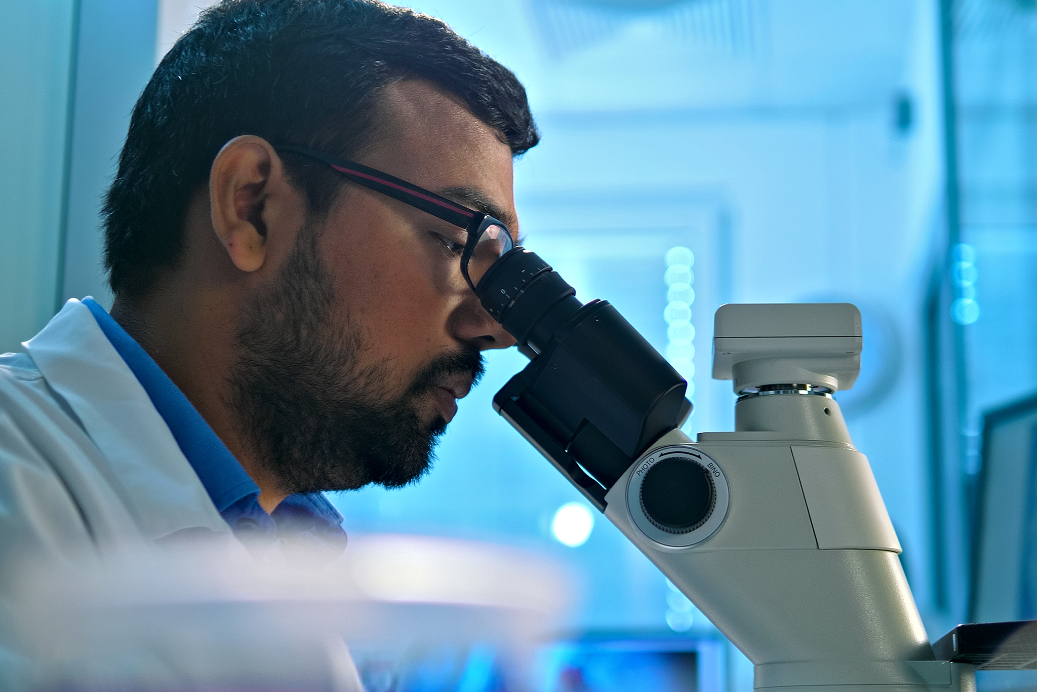 A researcher examines a sample under a microscope in a modern lab, highlighting meticulous scientific investigation and precision in medical research.