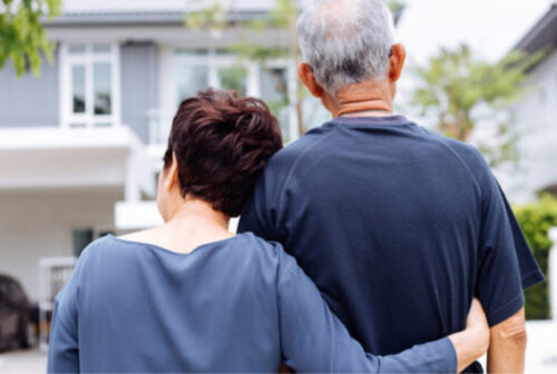 senior couple standing outside looking at their home
