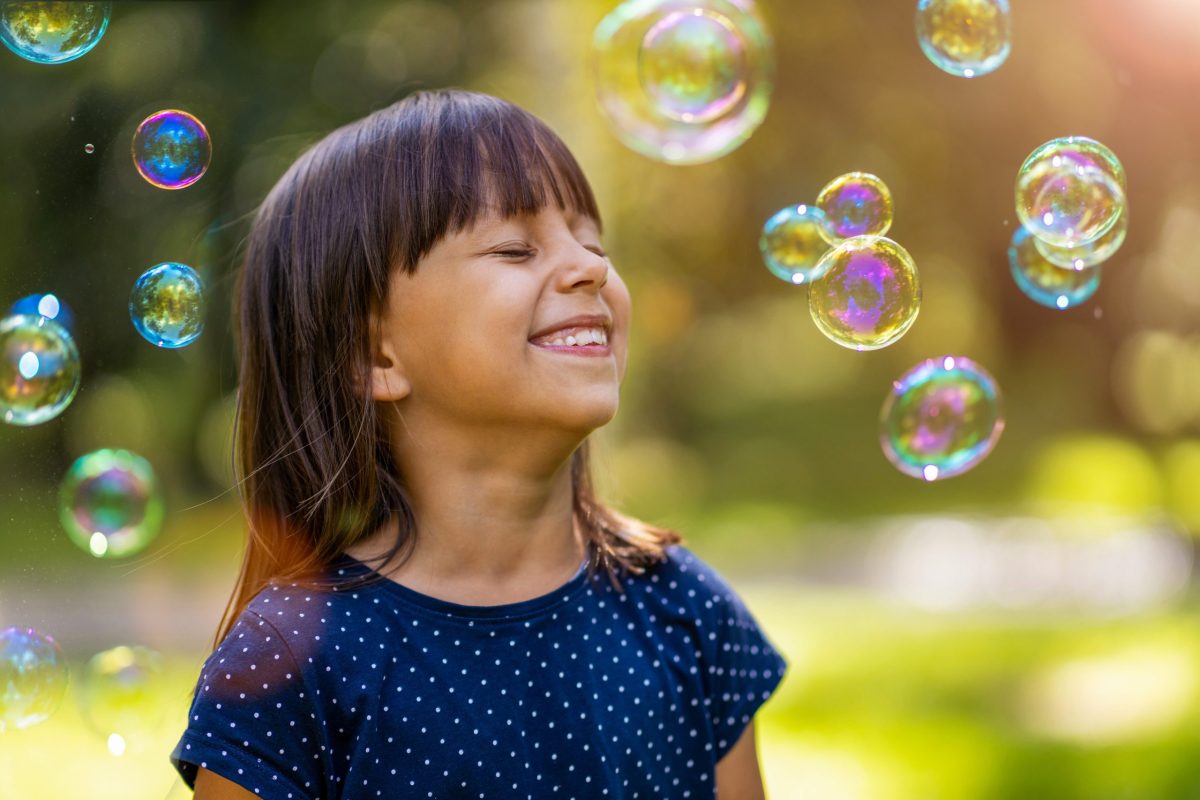 Young girl smiling playing in bubbles