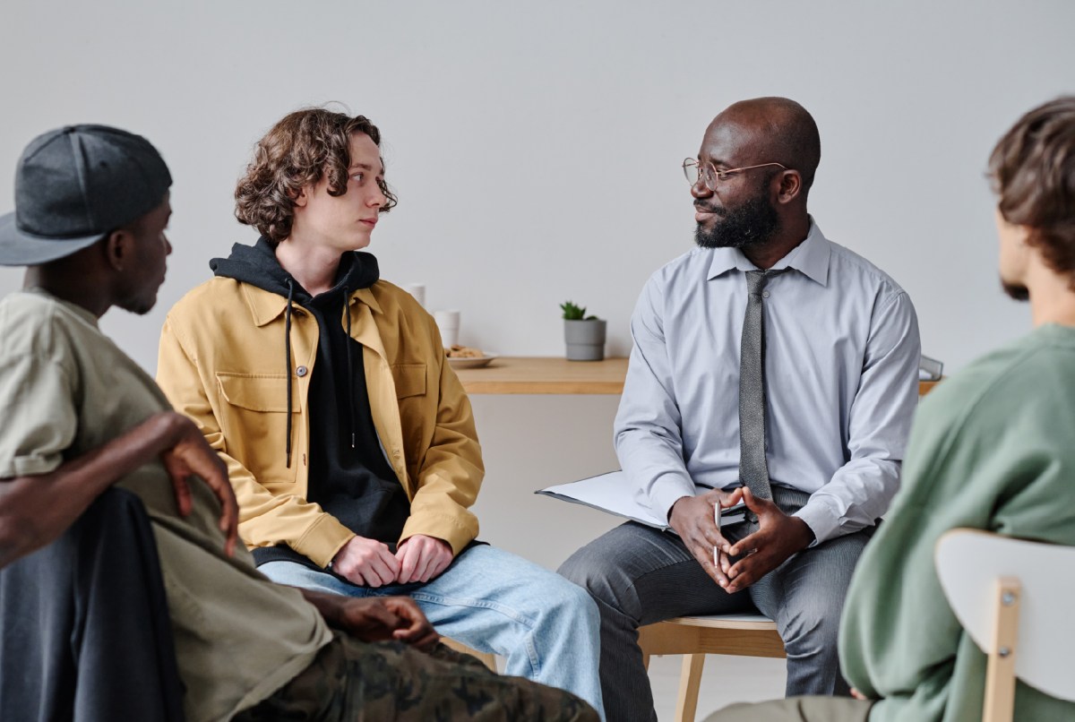 Group of students sitting on chairs and talking to therapist