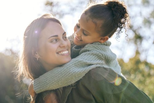 Happy, piggyback and a mother and child in a park for playing, bonding and quality time. Smile, hug and a young mom with a girl kid in nature with love, care and happiness